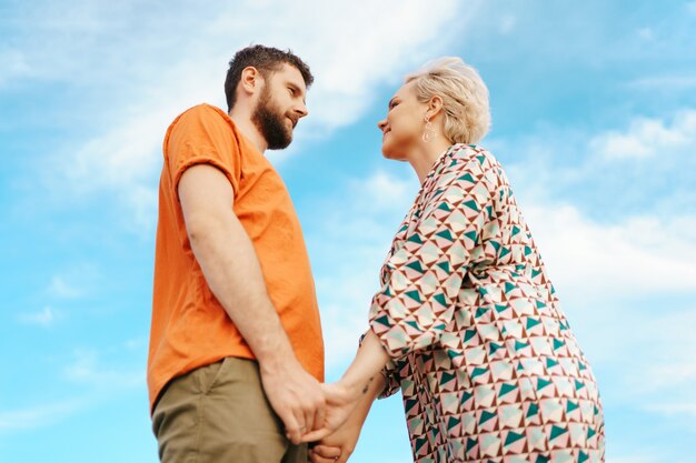 Heureux jeune couple en vêtements colorés avec ciel