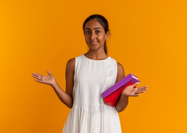 Heureux jeune écolière tenant des livres et écarte les mains sur l'orange