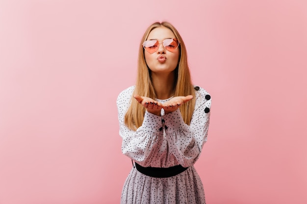 Heureux jeune femme envoyant un baiser aérien pendant la séance de portraits. Glamour femme caucasienne en chemisier décontracté exprimant l'amour.