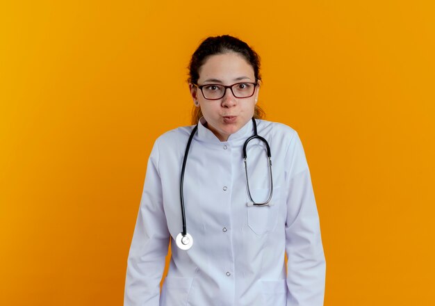 Heureux jeune femme médecin portant une robe médicale et un stéthoscope avec des lunettes isolées