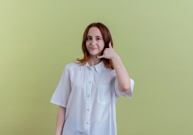 Heureux jeune fille rousse montrant le geste d'appel téléphonique isolé sur vert olive avec espace copie