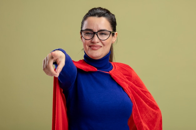 Photo gratuite heureux jeune fille de super-héros portant des lunettes vous montrant le geste isolé sur fond vert olive