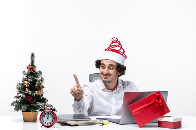 Heureux jeune homme d'affaires positif avec chapeau de père Noël drôle parlant à quelqu'un au bureau sur fond blanc