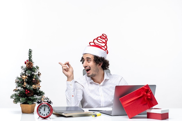 Heureux jeune homme d'affaires surpris positif avec drôle de chapeau de père Noël parlant à quelqu'un au bureau sur fond blanc