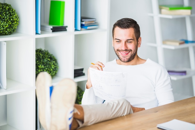 Heureux jeune homme d&#39;affaires travaillant sur un document sur le lieu de travail