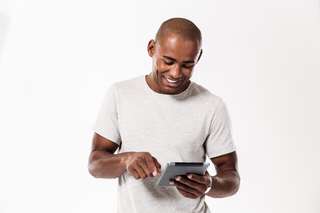 Heureux jeune homme africain à l'aide de la tablette tactile.