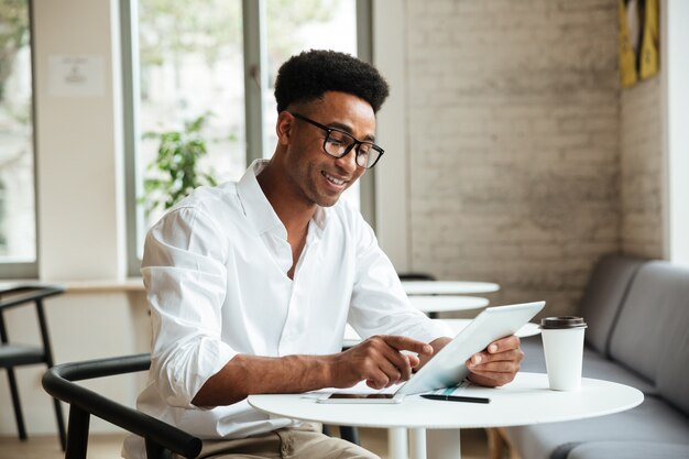 Heureux jeune homme africain assis coworking