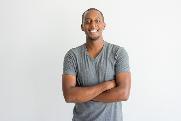 Photo gratuite heureux jeune homme africain excité en croisant les bras sur la poitrine et en regardant la caméra.