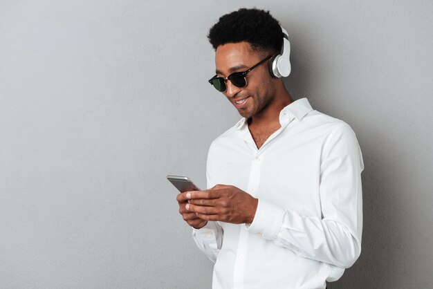 Heureux jeune homme africain en lunettes de soleil, écouter de la musique