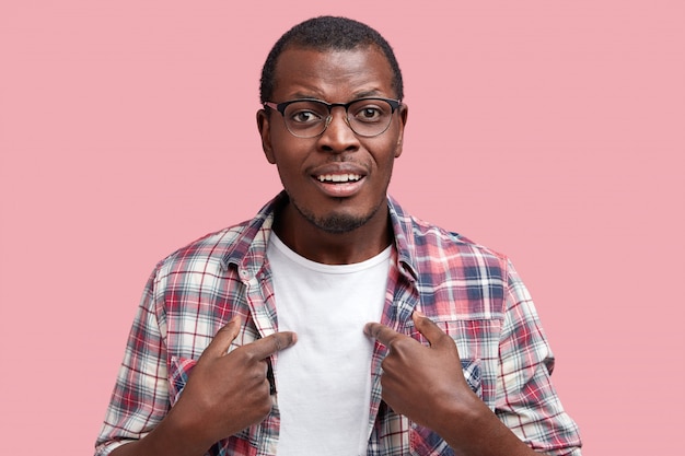 Heureux jeune homme afro-américain porte un t-shirt blanc et une chemise à carreaux, indique des vêtements avec un espace vide