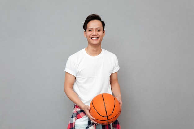 Heureux jeune homme asiatique avec ballon de basket