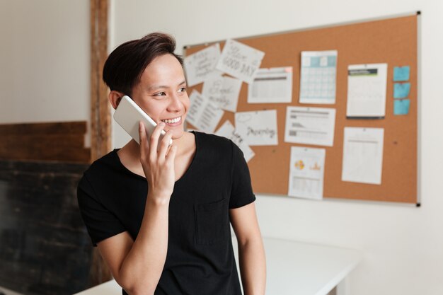 Heureux jeune homme asiatique debout à l'intérieur