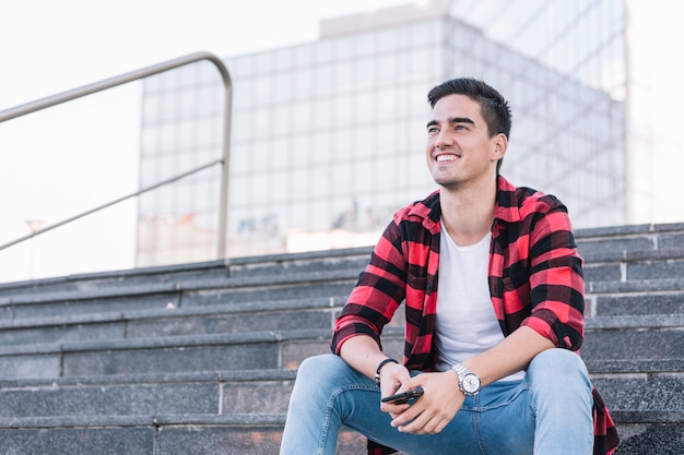 Heureux jeune homme assis sur l&#39;escalier