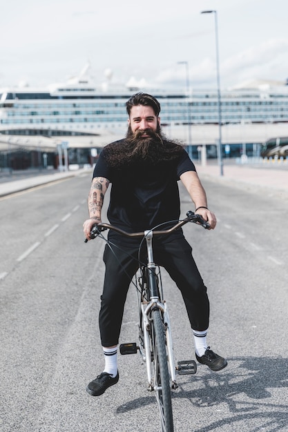 Heureux jeune homme barbu à bicyclette