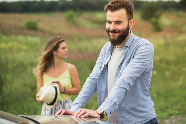 Heureux jeune homme debout devant une femme près de la voiture