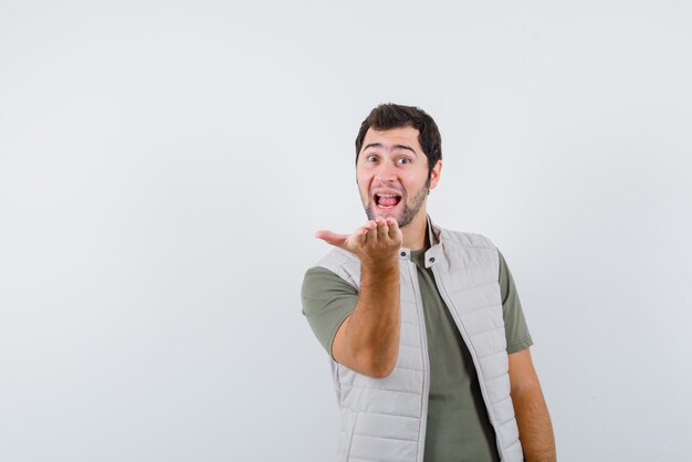 Heureux jeune homme étirant sa main gauche sur fond blanc