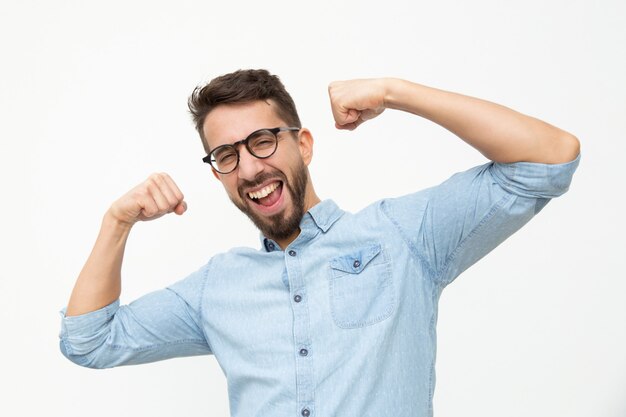 Heureux jeune homme montrant des biceps