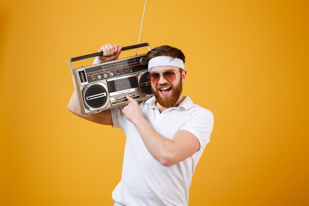 Heureux jeune homme portant des lunettes de soleil tenant un magnétophone