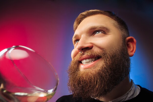 heureux jeune homme posant avec un verre de vin. Visage masculin émotionnel. Vue depuis le verre.