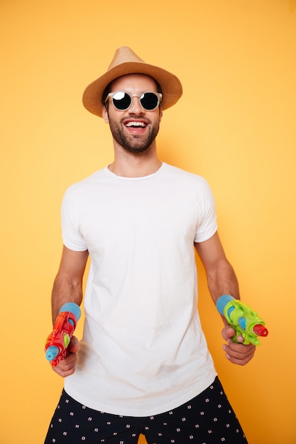 Photo gratuite heureux jeune homme tenant des pistolets à eau jouets