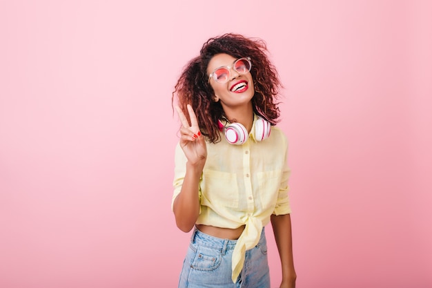 Heureux jeune mannequin en chemise d'été en riant. Fille africaine sincère aux cheveux bouclés relaxant