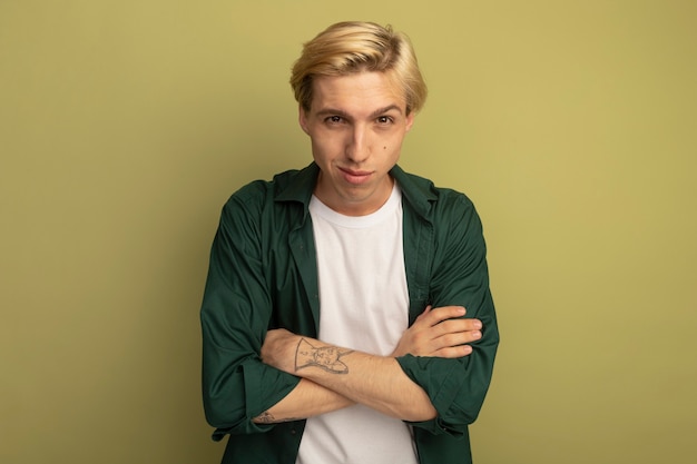 Photo gratuite heureux jeune mec blond vêtu d'un t-shirt vert croisant les mains