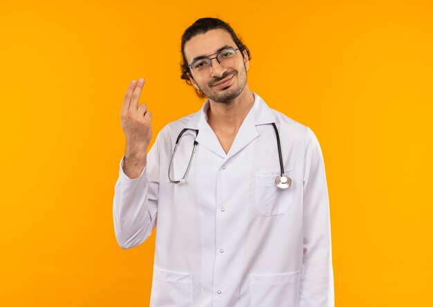 Heureux jeune médecin avec des lunettes médicales portant une robe médicale avec stéthoscope montrant deux