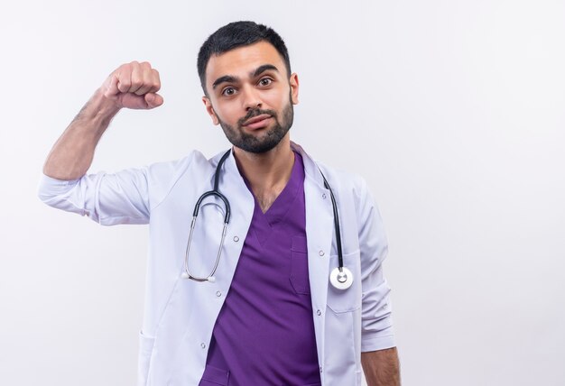 Heureux jeune médecin de sexe masculin portant une robe médicale stéthoscope faisant un geste fort sur fond blanc isolé