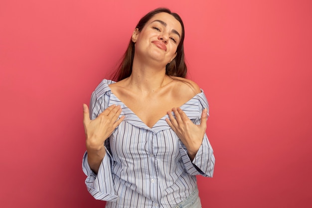 Photo gratuite heureux jolie femme caucasienne les mains sur la poitrine rose