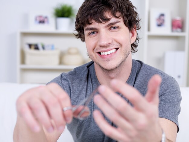 Heureux joyeux souriant bel homme coupant les ongles - à l'intérieur