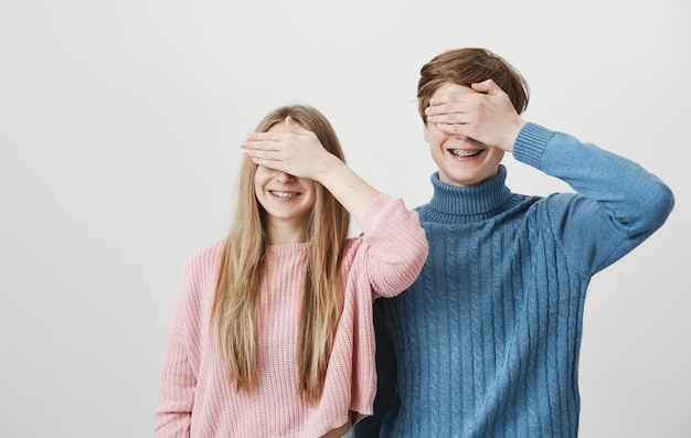 Photo gratuite heureux mec souriant et fille avec des accolades fermer les yeux avec des paumes