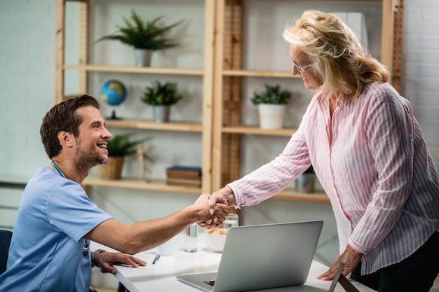 Photo gratuite heureux médecin serrant la main d'une femme âgée qui est venue à un rendez-vous médical