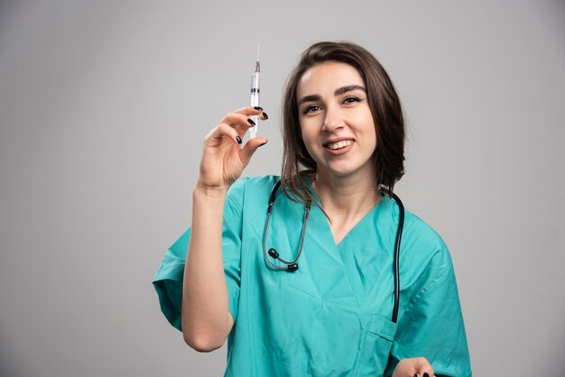 Heureux médecin en uniforme posant avec une seringue. Photo de haute qualité