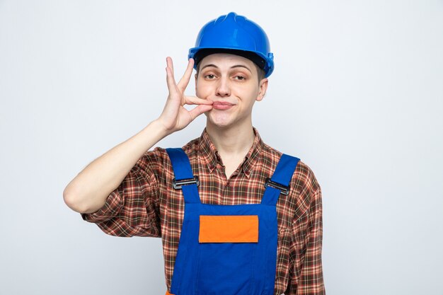 Heureux de montrer un geste délicieux jeune constructeur masculin en uniforme