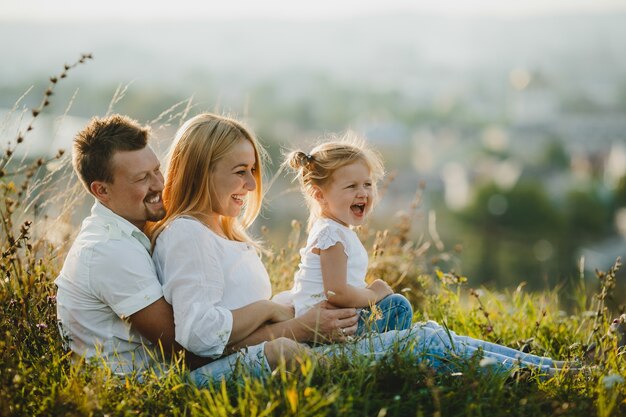 Heureux parents et leur petite fille reposent sur la pelouse lors d&#39;une belle journée d&#39;été