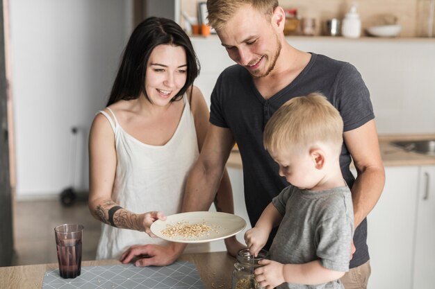 Heureux parents regardant petit garçon enlever l&#39;avoine du bocal dans la plaque