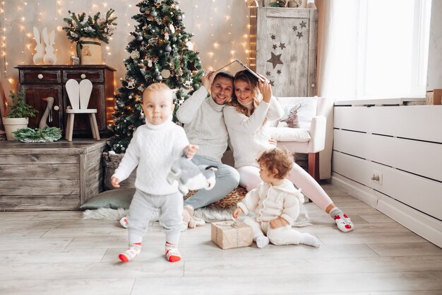 Heureux parents sous le toit d'un ordinateur portable ouvert regardant leurs enfants qui jouent. Temps de Noël.