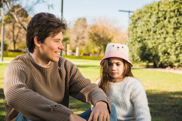 Heureux père assis devant sa fille dans le parc