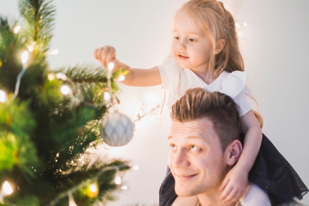 Heureux père à côté de l&#39;arbre de Noël illuminé avec sa fille