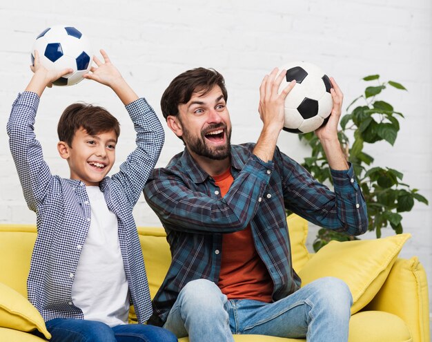 Heureux père et fils tenant des ballons de football