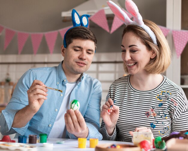 Heureux père et mère peignant des oeufs de Pâques