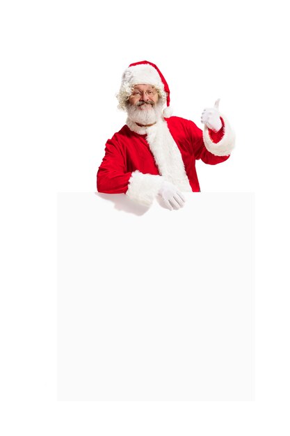 Heureux père Noël surpris pointant sur fond de bannière publicitaire vierge avec espace de copie. Homme senior souriant montrant à blanc vierge d'affiche vide