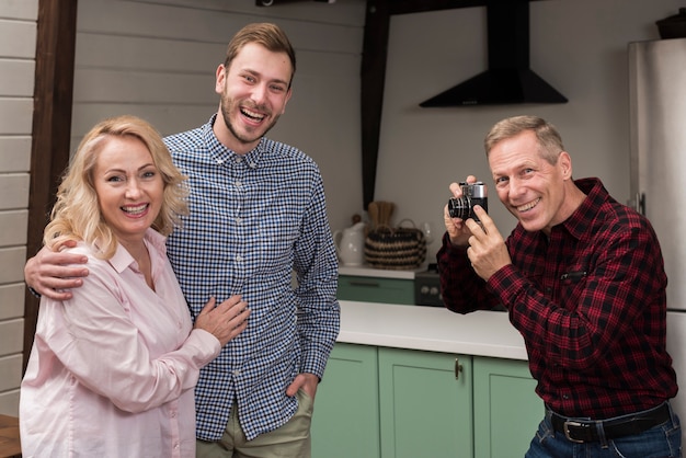 Heureux père prenant une photo de maman et fils dans la cuisine