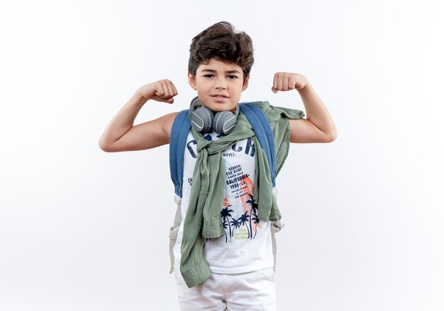 Heureux petit écolier portant sac à dos et écouteurs faisant un geste fort isolé sur fond blanc