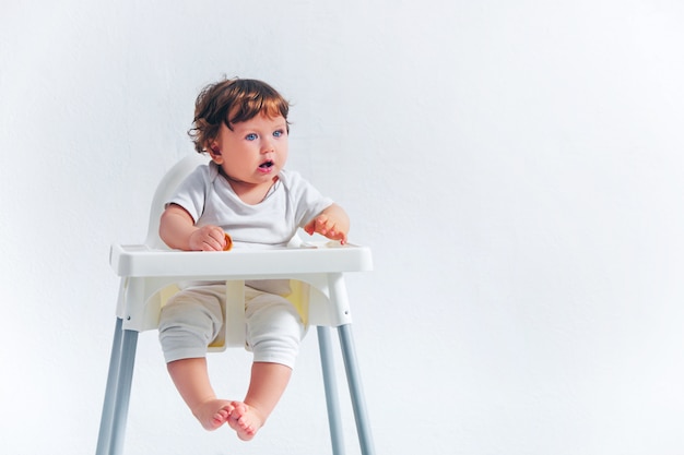 Heureux petit garçon assis sur une chaise bébé