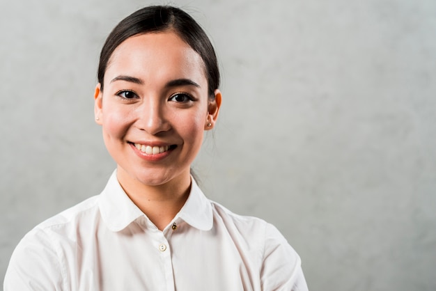 Heureux portrait d&#39;une jeune femme asiatique debout sur un fond gris