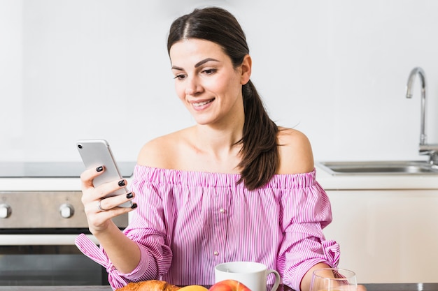 Photo gratuite heureux portrait d'une jeune femme à la maison avec un téléphone portable