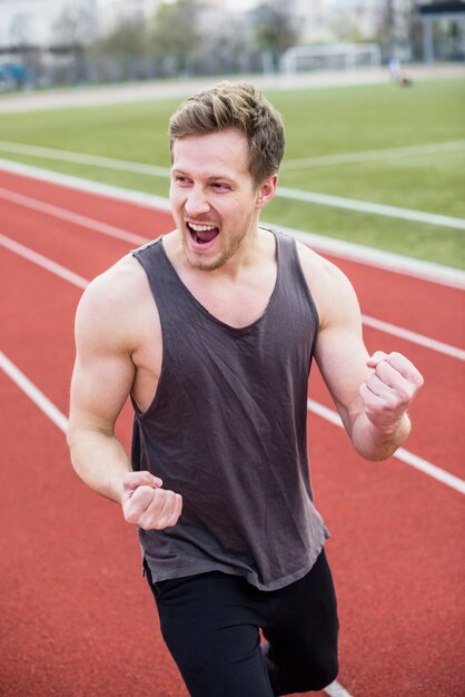 Heureux portrait de jeune homme excité, serrant son poing dans le stade