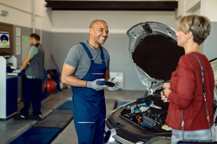 Photo gratuit heureux réparateur automobile afro-américain parlant au client dans un atelier