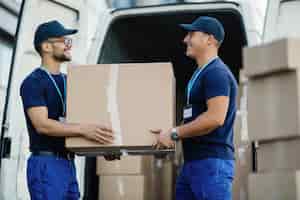 Photo gratuite heureux travailleur manuel coopérant tout en transportant des boîtes en carton dans une camionnette de livraison